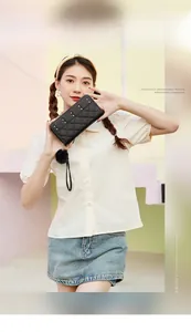 Close-up of quilted black wallet featuring silver studs and a plush ball charm detail