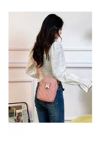 Detail view of pink quilted shoulder bag with a cute white bunny pendant and slim strap