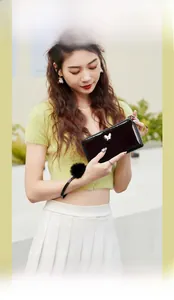 Close-up of black patent leather wallet featuring silver butterfly and fur ball wristlet