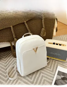 Detailed view of white crocodile pattern backpack with gold V logo in cozy home setting