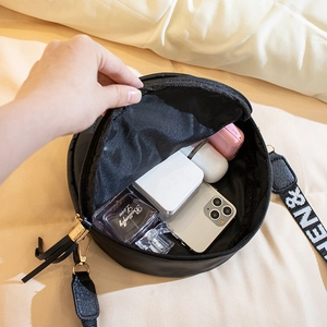 Black round crossbody bag with embroidered strap and spacious interior for daily essentials