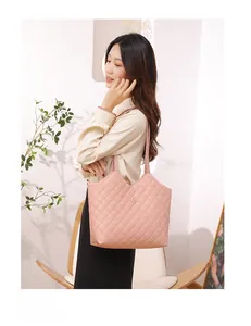 Pink quilted tote bag with golden flower logo shown on a model in a minimalist room