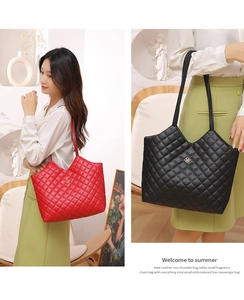 Detail of quilted leather tote bag with elegant gold clover hardware and twin handles