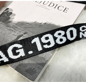 Détail de la bandoulière noire avec lettrage AG.1980 sur fond de fausse fourrure blanche