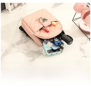 Internal storage of a quilted pink backpack with daily essentials on a marble surface