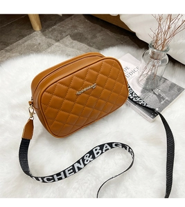 Detail of brown quilted crossbody bag with golden logo and patterned wide strap