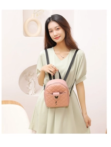 Close-up of pink quilted mini backpack with metal bear buckle on a green dress model