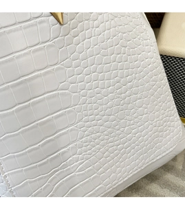 Detail shot of white crocodile embossed leather and golden triangle hardware on backpack
