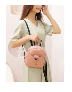 Detailed view of pink quilted mini backpack with golden bear charm and black strap