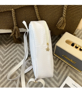 Close-up of white crocodile pattern backpack with golden flower zipper and side texture