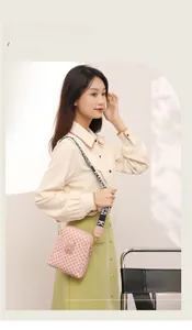 Detail of pink monogram crossbody bag with a wide black logo shoulder strap on a model
