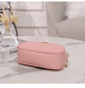 Détail du sac bandoulière en cuir matelassé rose avec fermoir papillon doré et chaîne