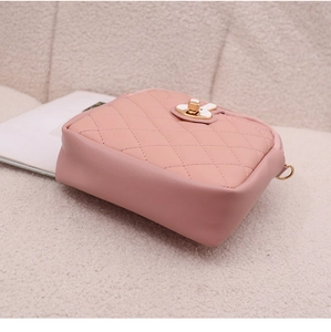 Detail of pink quilted crossbody bag featuring a golden rabbit twist lock and PU texture