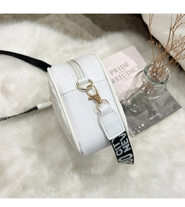 Macro detail of white quilted crossbody bag featuring gold hardware and jacquard strap