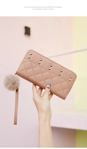 Détail du portefeuille rose matelassé avec clous dorés et pompon en fausse fourrure