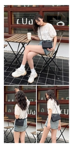 Outdoor lifestyle view of black crossbody bag with circular cutout details and strap