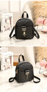 Detail of black quilted mini backpack with gold charms on elegant marble tabletop