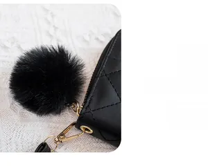 Detailed macro view of black quilted leather texture with a decorative fur ball keychain
