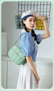 Detailed view of light green quilted leather underarm bag with gold hardware detail