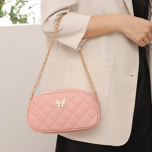 Sac matelassé rose avec décoration papillon en émail blanc porté par un mannequin