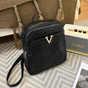 Fashionable black crocodile pattern backpack with golden V-logo on a textured carpet
