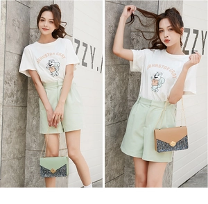 Detail of glitter patchwork crossbody bag with metal chain strap and logo graphic T-shirt