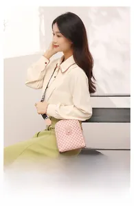 Lifestyle shot of pink crossbody bag with diamond pattern and wide fabric strap