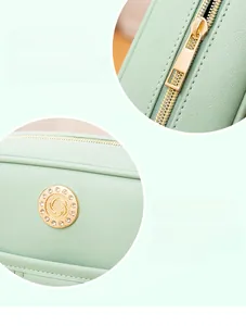 Close-up of smooth gold zipper and pebble leather texture on light green handbag