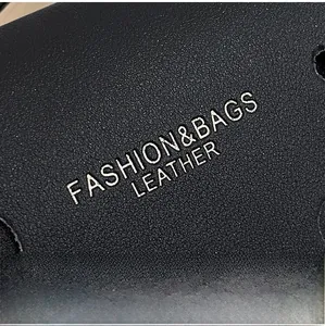 Macro detail of black lychee grain leather texture with silver fashion text branding