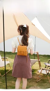 Dettaglio del mini zaino giallo senape con motivo vintage in un ambiente esterno