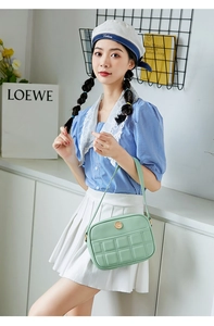 Detail of light green quilted handbag with golden circular logo and fine strap