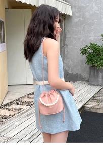 Detail of pink drawstring bucket bag with pearl handle and litchi texture