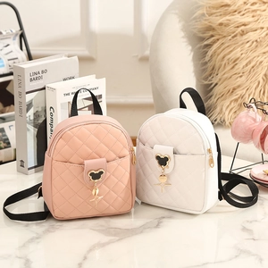 Quilted mini backpacks in pink and white with gold mouse ear charms on marble surface