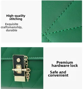 Detail of green leather stitching and black gold hardware lock with decorative chain