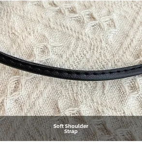 Detail of soft black leather shoulder strap with fine stitching on white texture
