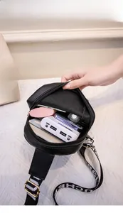 Vue de dessus d'un sac bandoulière noir montrant l'espace intérieur avec téléphone et objets