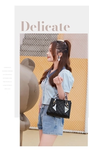 Detail of black quilted handbag with silk scarf handle detail held by a model