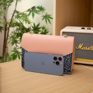 Pink and blue glitter crossbody bag with gold chain strap on a wooden tabletop