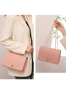 Detail of pink quilted square bag featuring gold-tone lock and elegant chain strap
