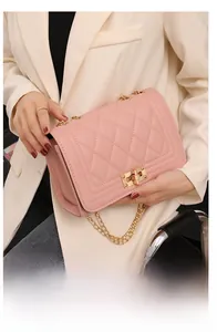 Detailed view of pink quilted handbag with gold chain strap and metallic lock closure
