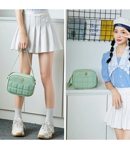 Detail of mint green quilted bag with golden emblem and elegant shoulder strap