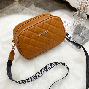 Brown quilted crossbody camera bag with adjustable wide strap and gold metal hardware