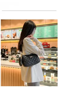 Détail d'un sac à bandoulière matelassé noir avec un porte-monnaie rond assorti