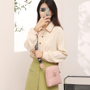 Classic light pink crossbody bag with patterned strap shown on a female model