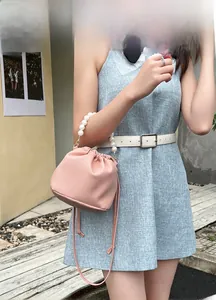 Pink lychee leather bucket bag featuring a large pearl handle and drawstring closure