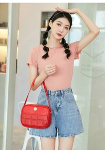 Close-up of red quilted shoulder bag with gold logo emblem on a female model