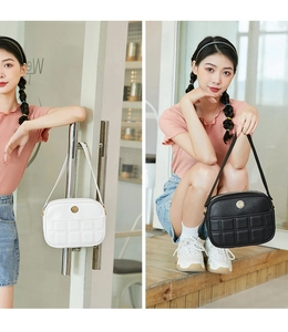 Detail of quilted leather handbag with round metal logo in classic black and white colors