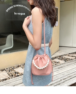 Pink drawstring bucket bag with lychee texture and large pearl handle detail