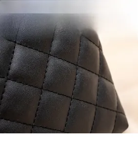 Macro detail of diamond quilted black leather texture with premium soft grain and stitching