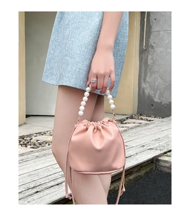 Detail of pink lychee pattern bucket bag with elegant white pearl handle and drawstring